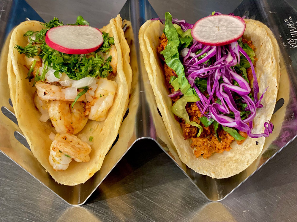 Two Yolpaqui tacos with fresh vegetables and cilantro
