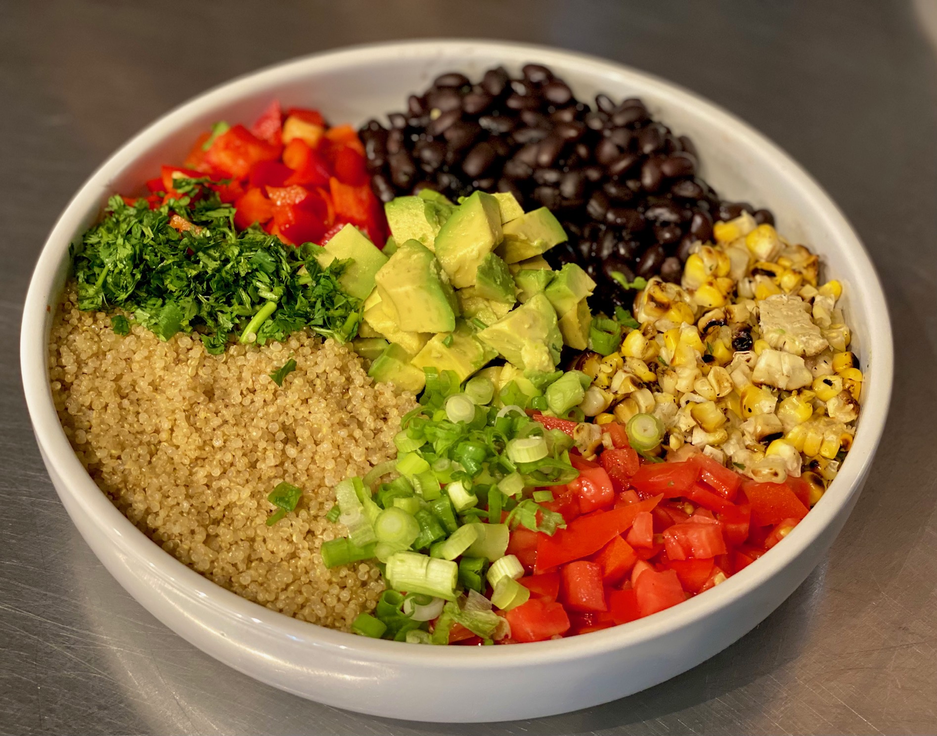 Colorful quinoa bowl with avocado, tomatoes, corn, black beans and cilantro
